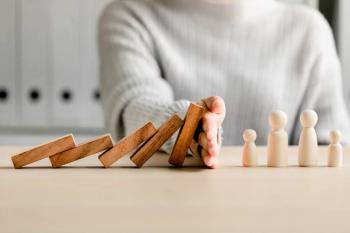 Hand blocking dominos Image credit: AdobeStock/sirichai