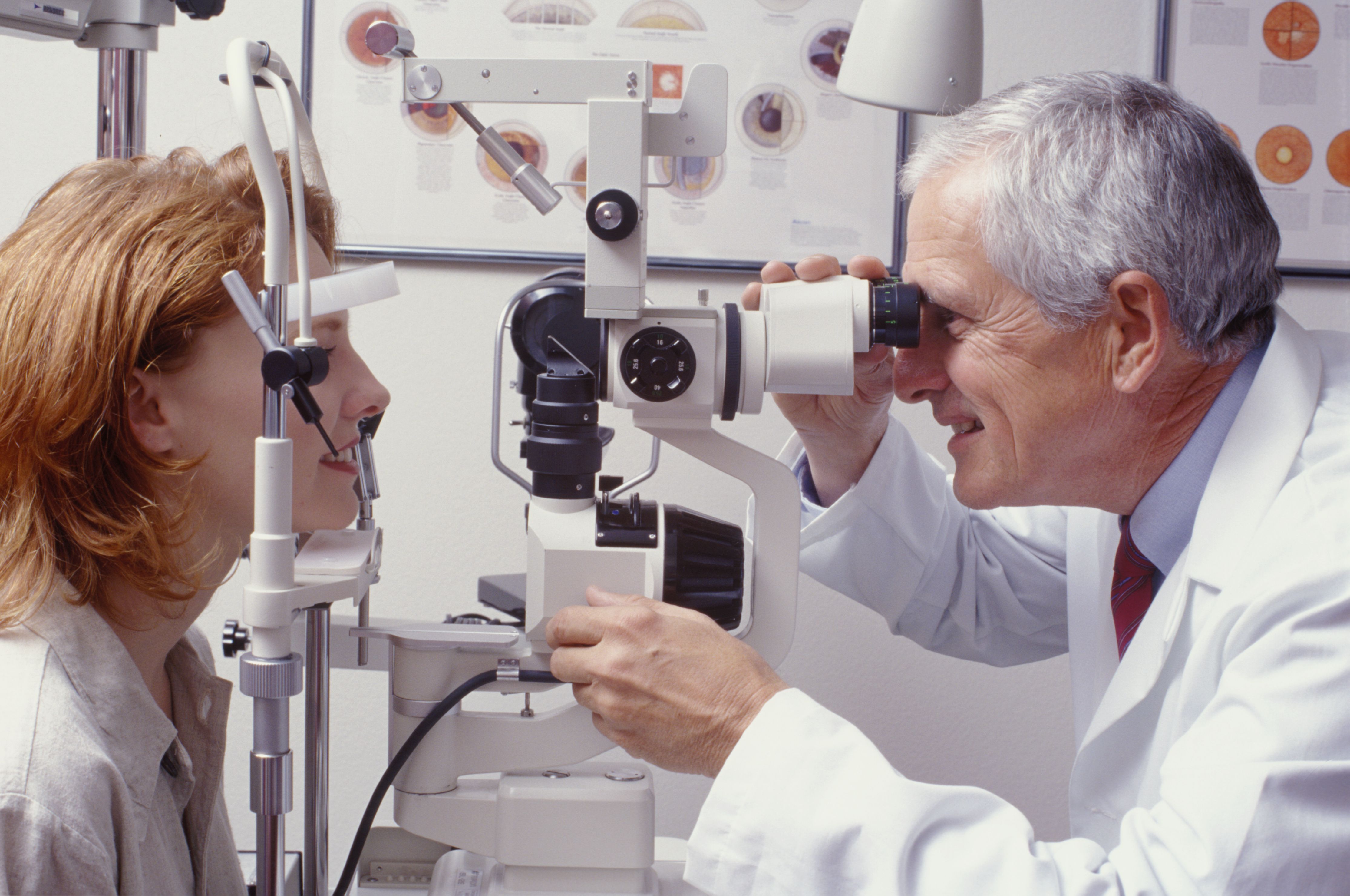 A male optometrist observes a female patient's eyes