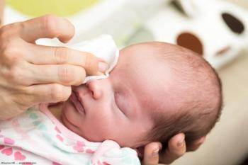 Baby having eye wiped with cloth Image credit: AdobeStock/Deymos.HR