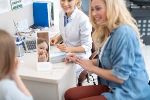 Child putting in contact lens with doctor and parent in doctor office Image credit: AdobeStock/YakobchukOlena