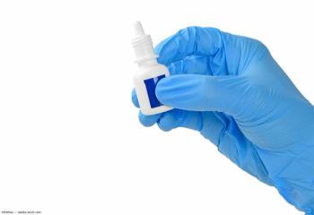 Gloved hand holding eye drop container Image Credit: ©Kitithat - adobe.stock.com