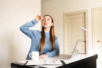 Woman at office desk administering eye drops Image credit: AdobeStock/СоняМонштейн
