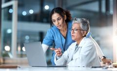 Doctors talking at table Image credit: AdobeStock/CMalambo/peopleimages.com