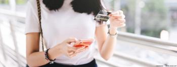 A woman holding a phone and credit card. Image credit: AdobeStock/dodotone