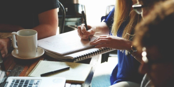 woman takes notes next to another person