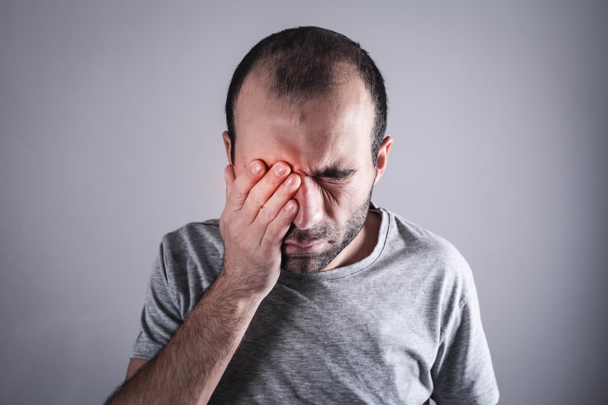 Man holding eye in pain Image credit: AdobeStock/andranik123