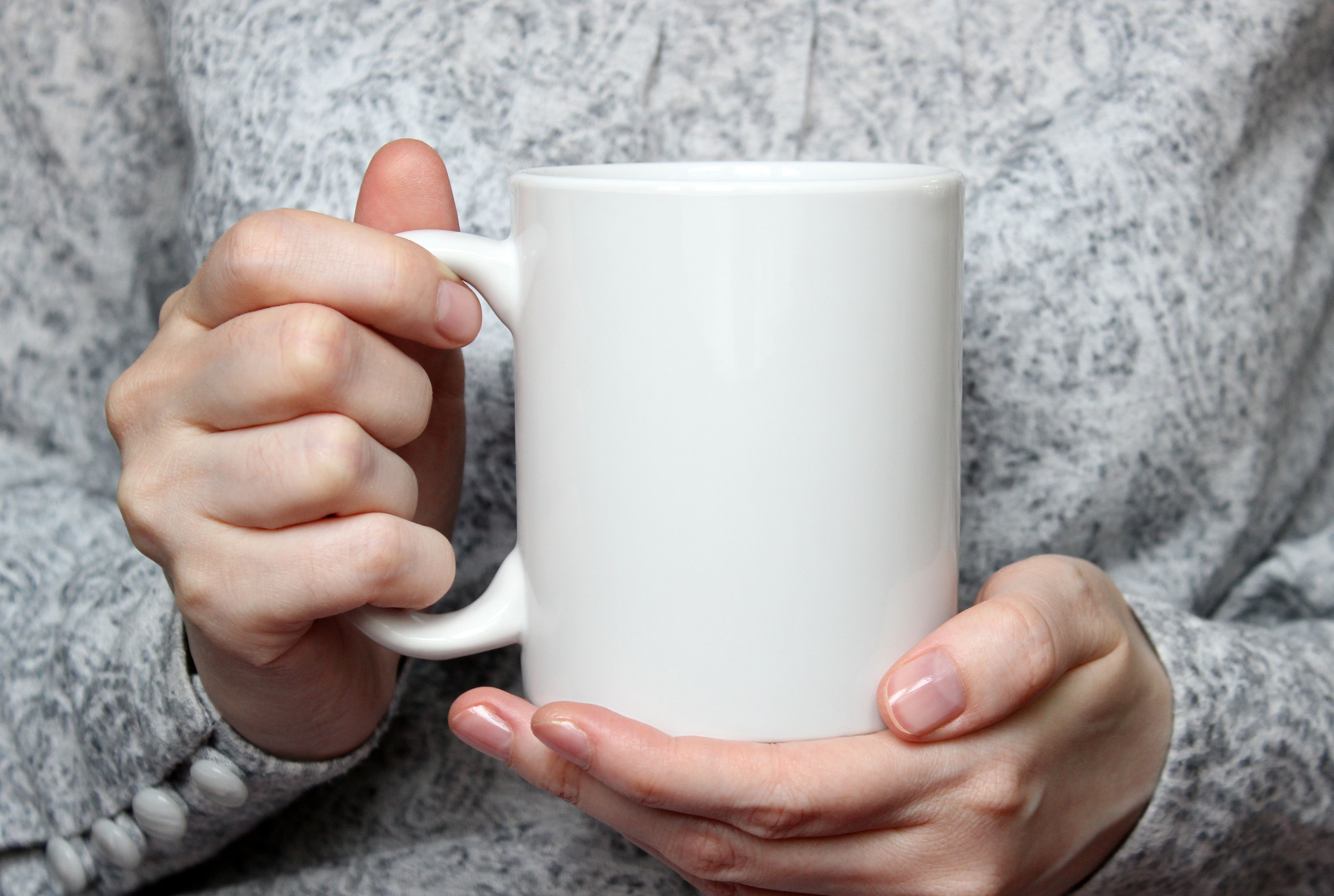 Girl holding white cup in hands. White mug in woman's hands.