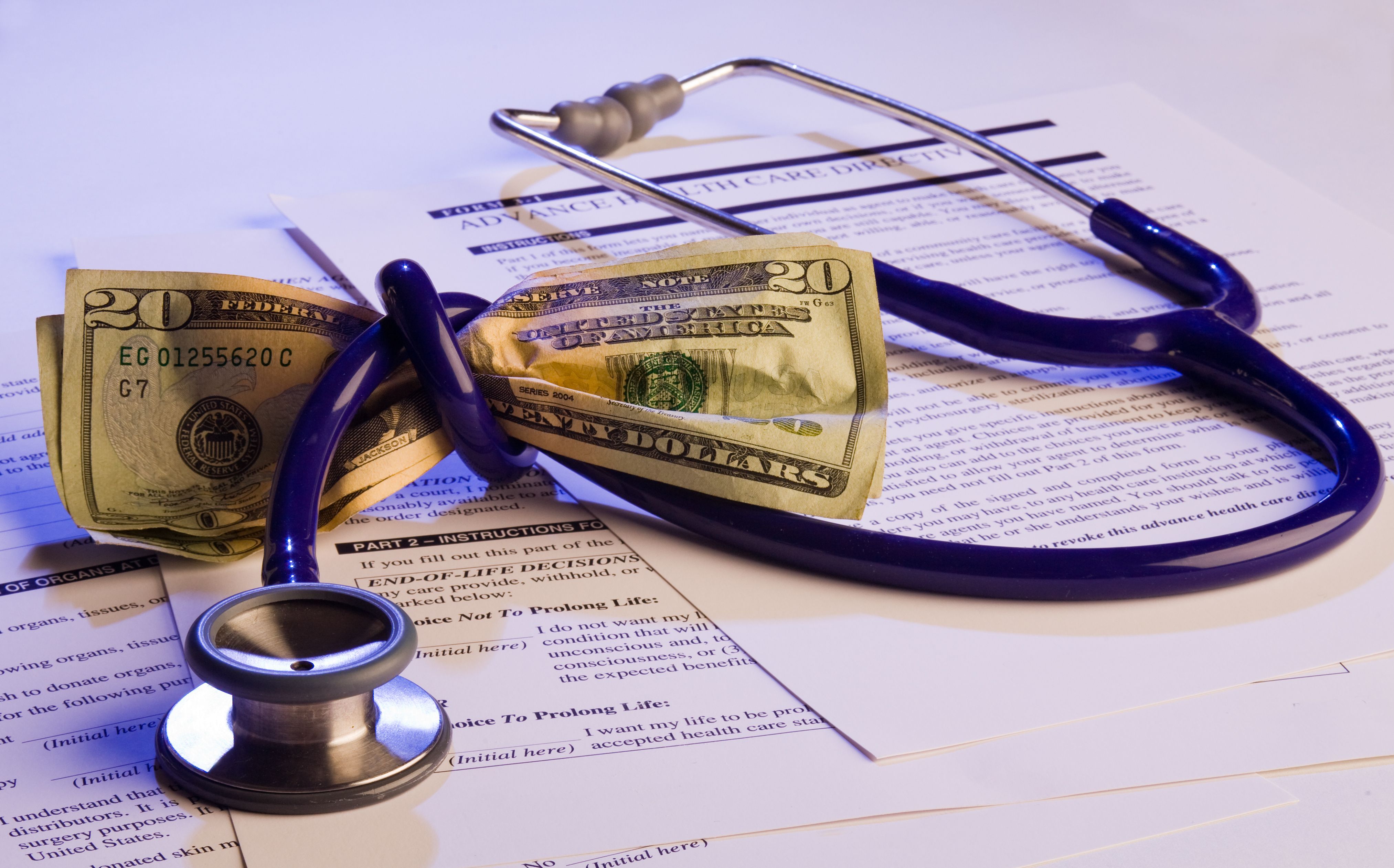 money wrapped in stethoscope with medical papers