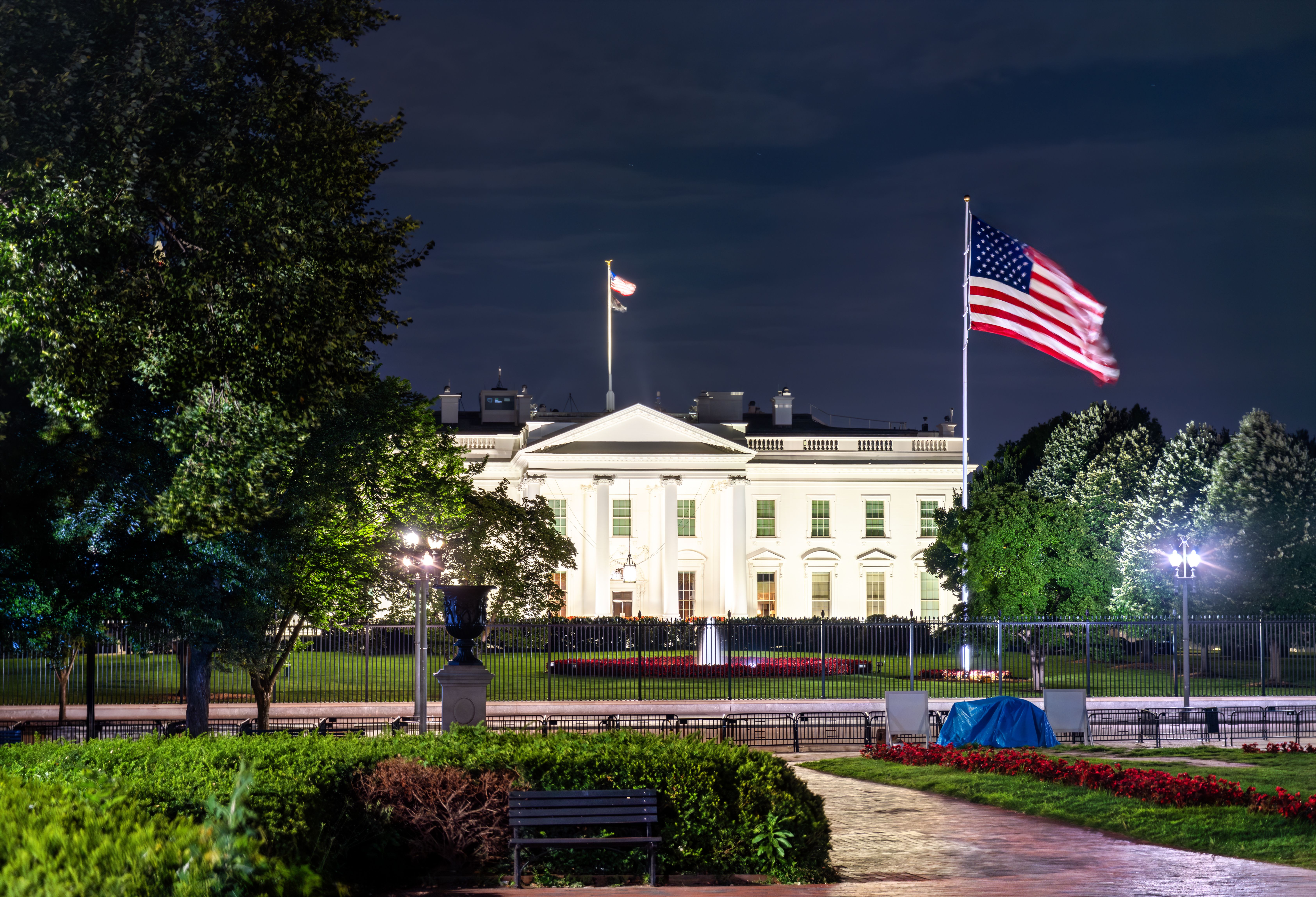 The White House, the official residence of the U.S. President, viewed from Lafayette Square in Washington, D.C. The historic neoclassical building with a United States flag are illuminated at night | © Leonid Andronov - stock.adobe.com