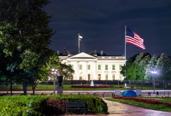 The White House, the official residence of the U.S. President, viewed from Lafayette Square in Washington, D.C. The historic neoclassical building with a United States flag are illuminated at night | © Leonid Andronov - stock.adobe.com
