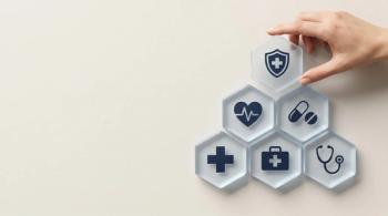 Hand placing a hexagonal tile with a shield and cross icon on a pyramid of health and medical service symbols, representing comprehensive healthcare and insurance. | © Abimusa Gallery - stock.adobe.com (2073964658)