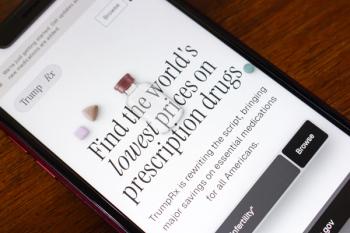 Angled close-up of smartphone showing TrumpRX website with medicine bottle and pills, discussing lower prescription drug prices in America today. | © Koshiro K - stock.adobe.com (1923384963)