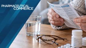 Elderly person read medicine leaflet on wooden table with water glass and pills | Sandor - stock.adobe.com