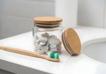 Glass jar with toothpaste tablets and bamboo toothbrush for zero waste oral care routine | Image Credit: Ana | stock.adobe.com
