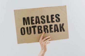 Hand holding a banner reading "measles outbreak" | Image Credit: © AndriiKoval - stock.adobe.com