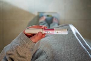 Woman standing on a scale holding Wegovy (semaglutide) injectable pen -- Image credit: Cynthia | stock.adobe.com