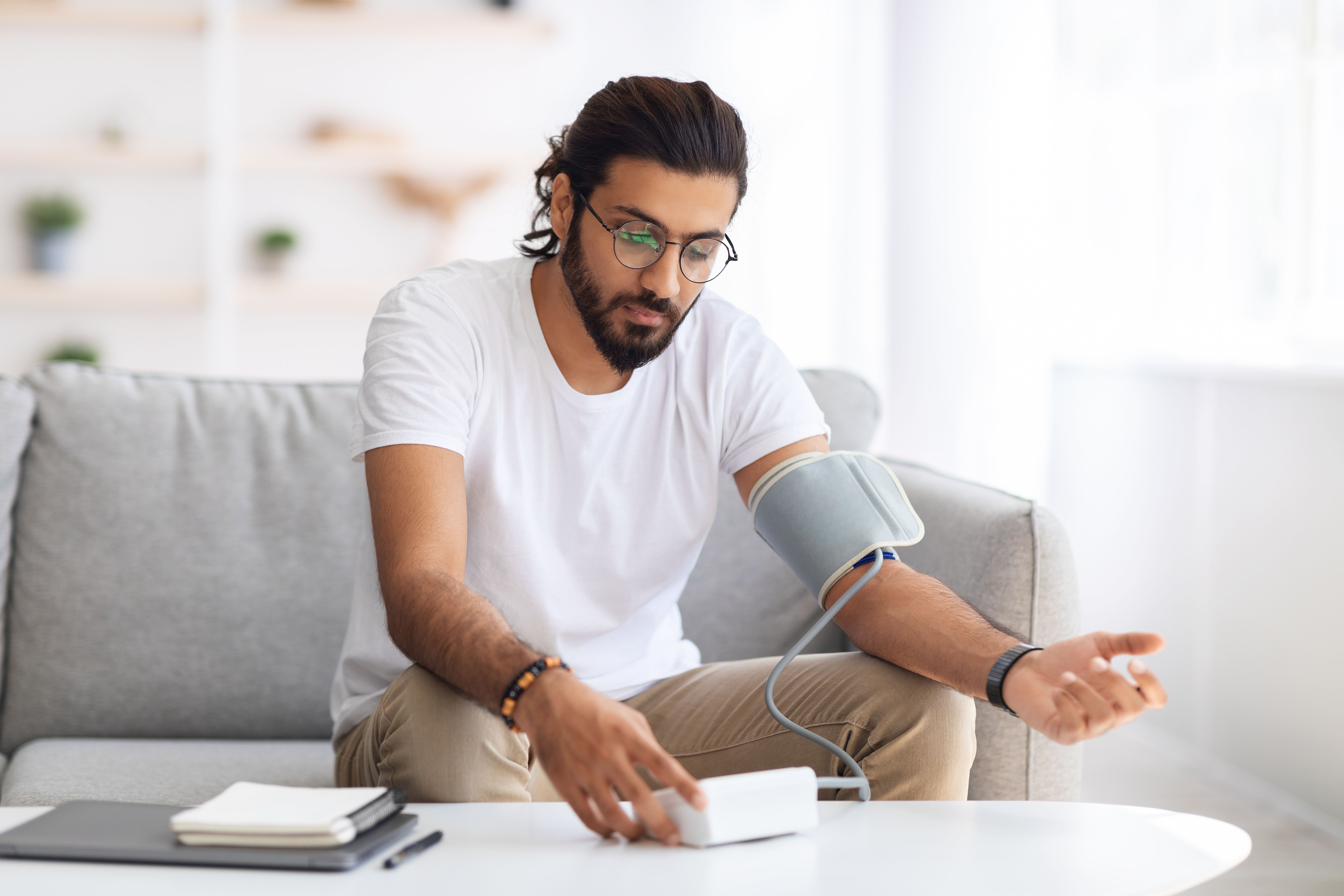 Man sitting checking blood pressure at home | Image Credit: Prostock-studio - stock.adobe.com