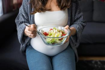 Pregnant woman eating fresh vegetable salad, sitting on a sofa, healthy pregnancy concept - Image credit: Anna | stock.adobe.com