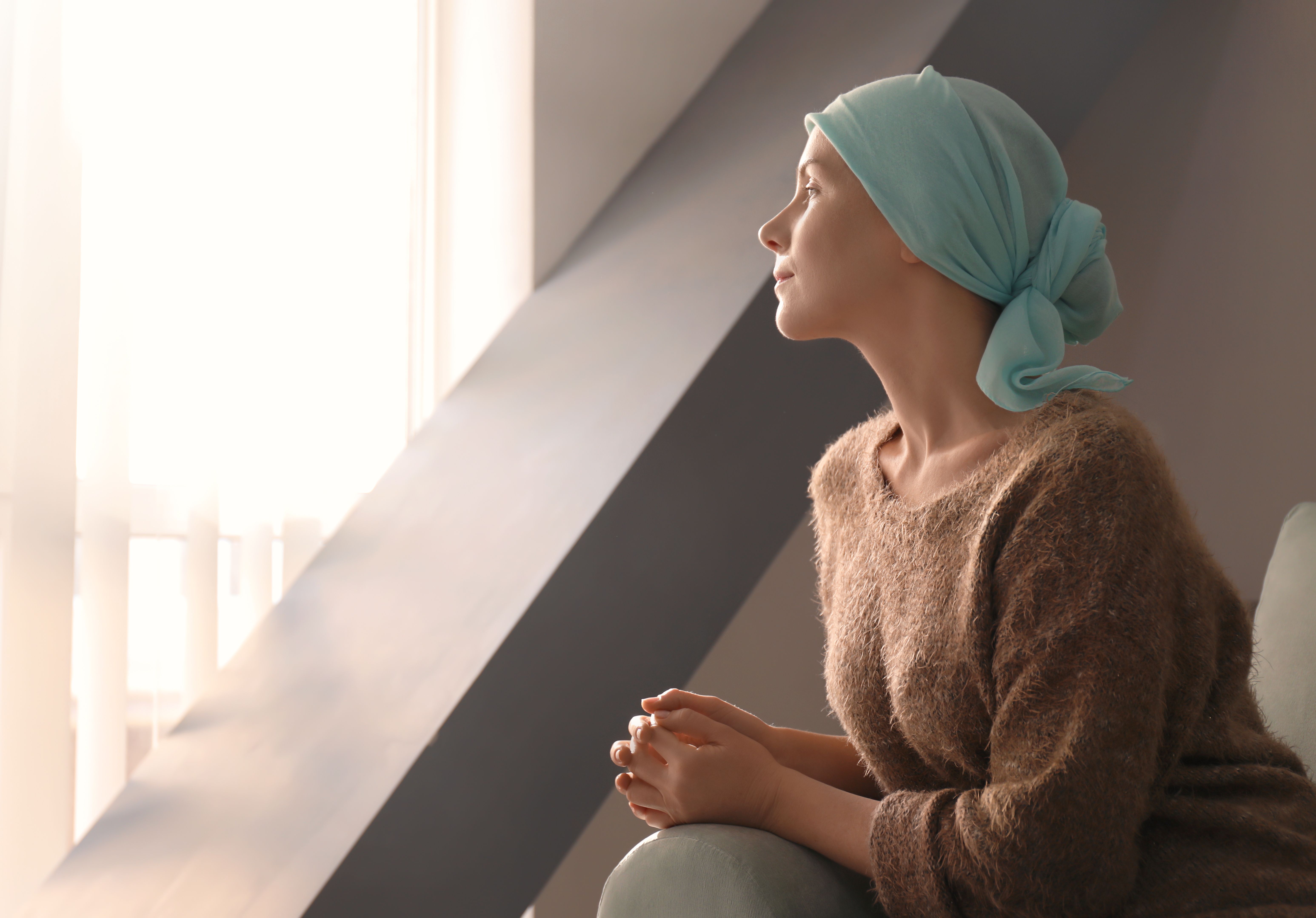 Young woman with cancer in headscarf indoors - Image credit: Africa Studio | stock.adobe.com