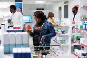 Woman customer searching pharmacy shelves for over the counter pills and supplements, focused on finding medication and health products while reading the labels from dispensary. | Image Credit: DC Studio | stock.adobe.com