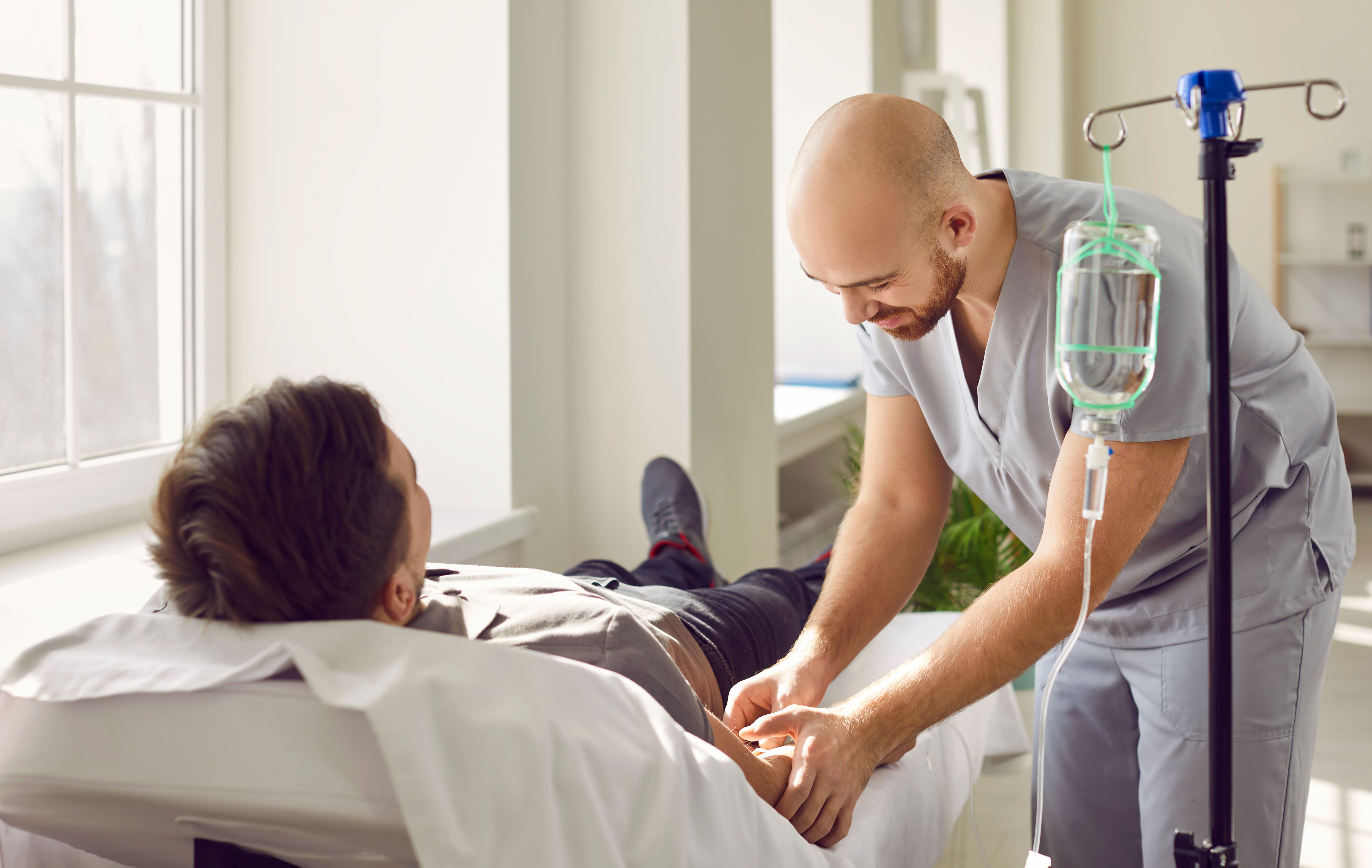 Health care worker inserting IV into patient's arm