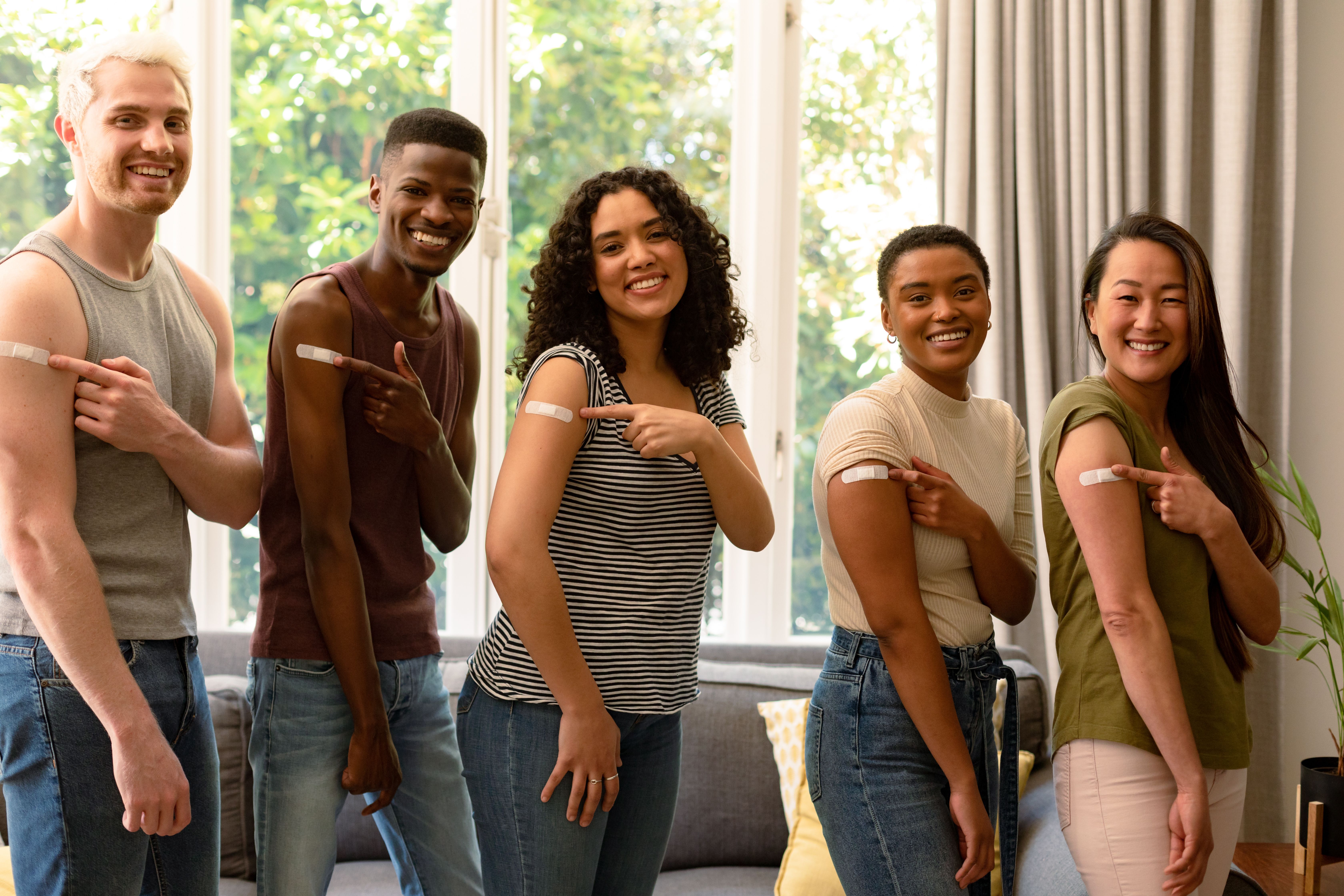 Group of happy friends showing plasters after vaccination | Image Credit: wavebreak3 | stock.adobe.com