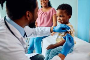 Smiling boy receiving vaccine at pediatrician's office. | Image Credit: Drazen | stock.adobe.com
