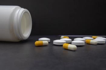 Close up open white bottle with medicine pills and capsules on dark background | Image credit: Yuriy Redkin- stock.adobe.com