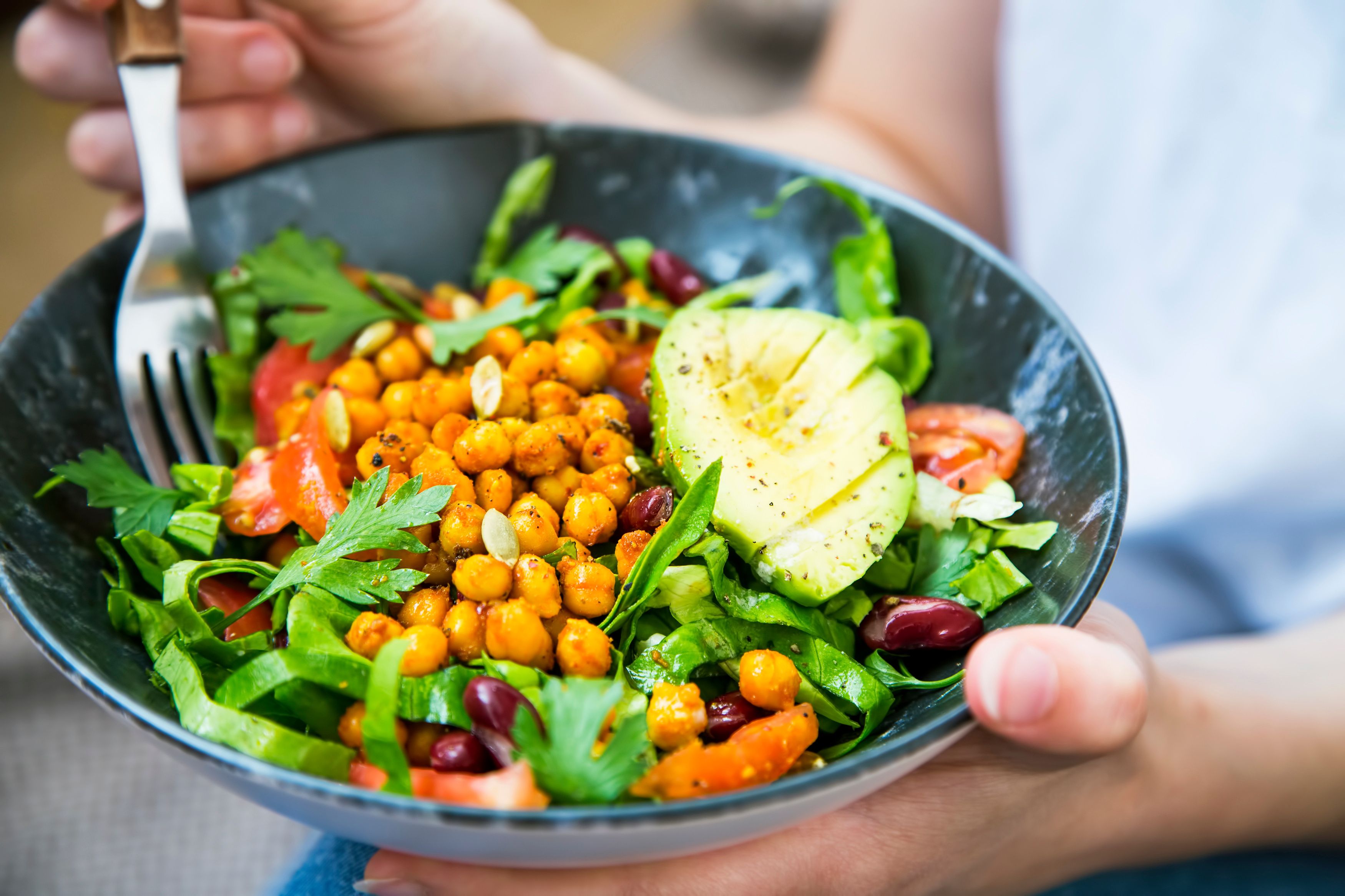 Clean eating, vegan healthy salad bowl closeup , woman holding salad bowl, plant based healthy diet with greens, chickpeas and vegetables - Image credit: marrakeshh | stock.adobe.com
