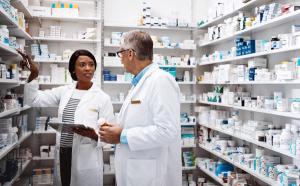 Medical, people and conversation with tablet in pharmacy for inventory, update and prescription. Healthcare, intern and pharmaceutical student with mentor by pills for dispensary, training or support - Image credit: ReeseArcurs/peopleimages.com | stock.adobe.com