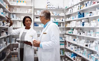 Medical, people and conversation with tablet in pharmacy for inventory, update and prescription. Healthcare, intern and pharmaceutical student with mentor by pills for dispensary, training or support - Image credit: ReeseArcurs/peopleimages.com | stock.adobe.com