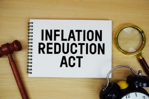 Inflation Reduction Act text written on notepad with pen, alarm clock and judge gavel on wooden background | Image Credit: © may1985 - stock.adobe.com