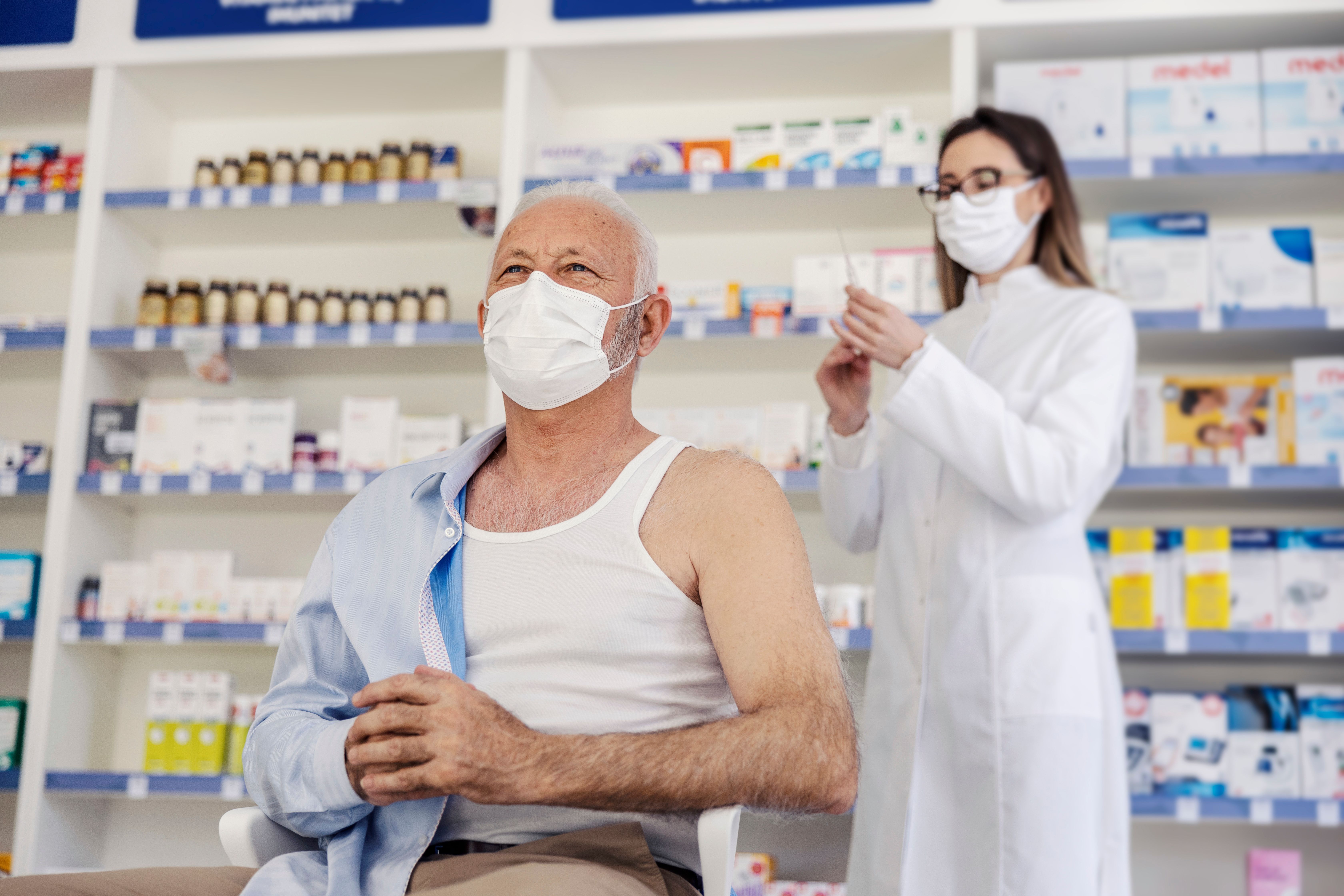 Therapy in a nursing home pharmacy. Female pharmacist gives therapy to a senior man who is sitting on a chair and has taken off his shirt. Vaccination, corona virus breaking news - Image credit: dusanpetkovic1 | stock.adobe.com