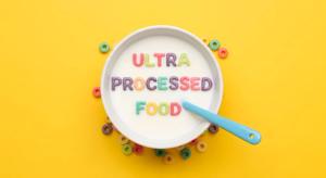 A bowl of cereal with the words "ULTRA PROCESSED FOOD" written on it, surrounded by cereal pieces. | Image Credit: Mono | stock.adobe.com