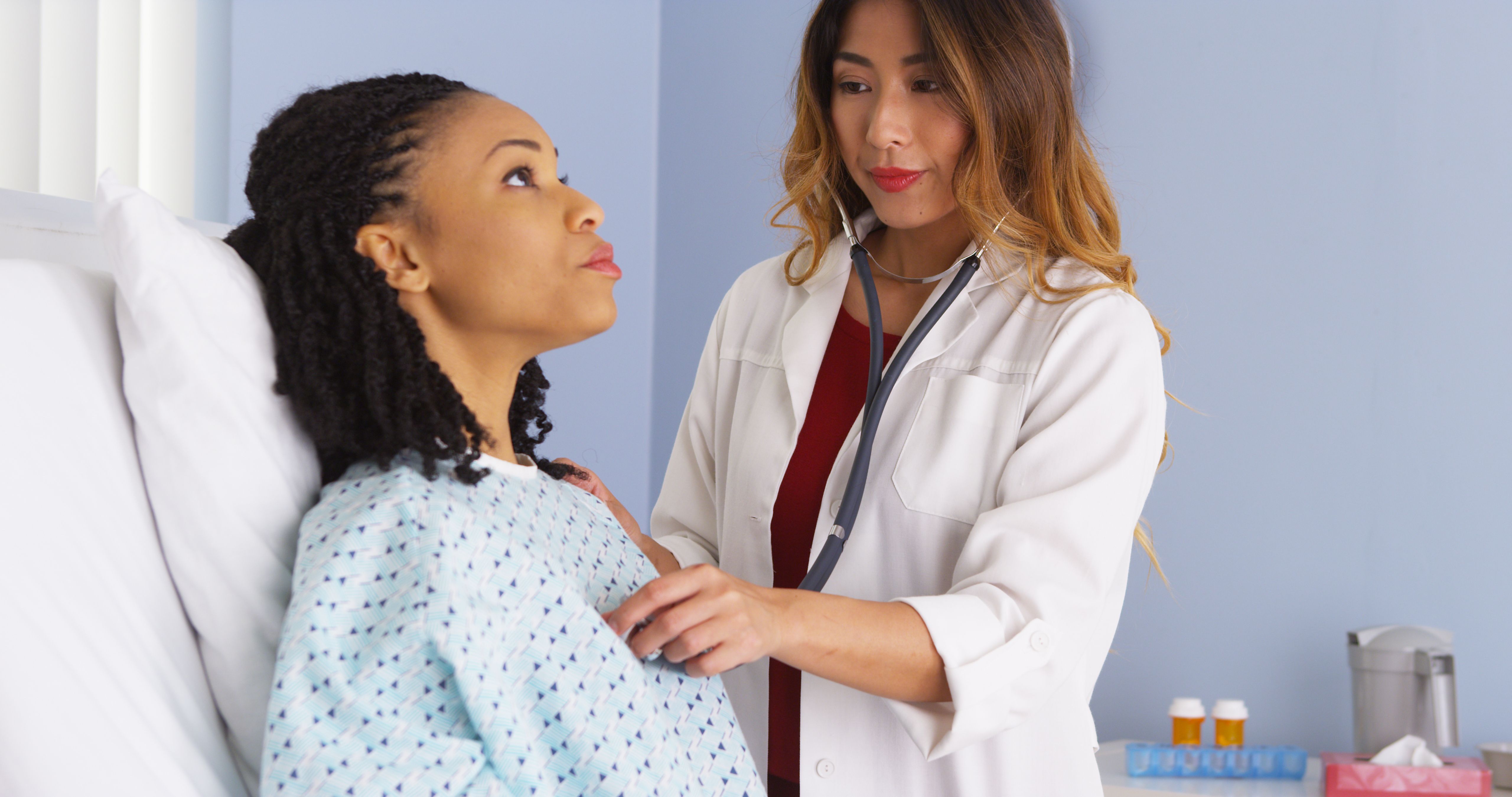 doctor listening to heart and lungs of black patient in bed | Image Credit: rocketclips - stock.adobe.com