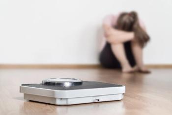 Weight loss fail concept. Scale and depressed, frustrated and sad woman sitting on floor holding head and arms on knees. | Image Credit: terovesalainen | stock.adobe.com