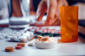 Blurred hand reaches for the orange pills laying on the table. Many other tablets laying blurred on the table near the spilled pills - Image credit: Svyatoslav Lypynskyy | stock.adobe.com 