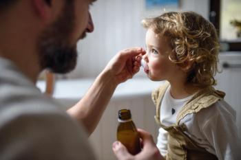 Parent giving their child an antibiotic -- Image credit: Halfpoint | stock.adobe.com
