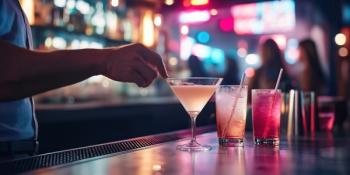 A man's hand is captured in the act of spiking a drink at a bustling bar or club | Image Credit: WD Stock Photos | stock.adobe.com