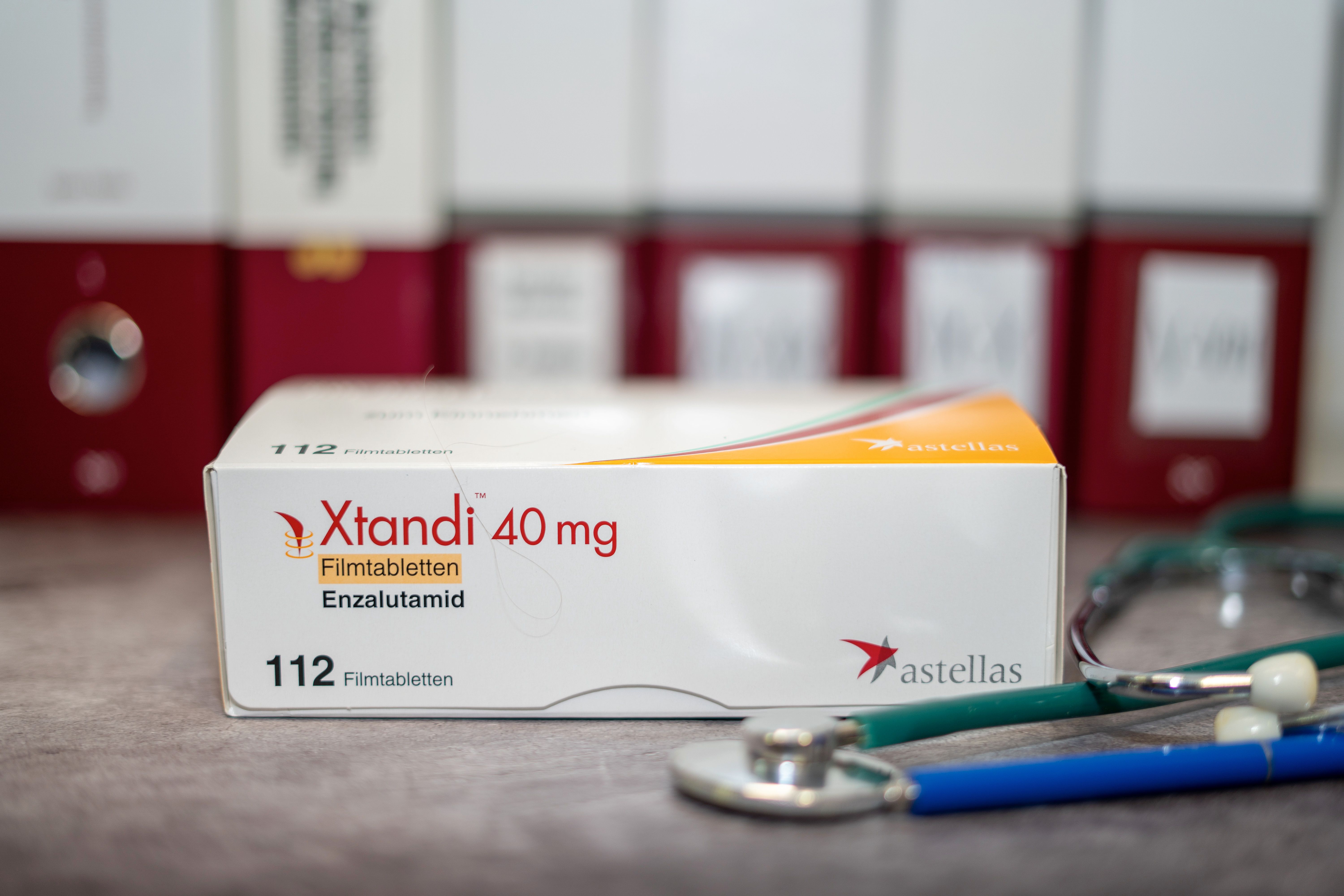 A Drug box of Xtandi containing Enzalutamide for treatment of prostate cancer on a table and in the background different medical books. Image Credit: omar | stock.adobe.com