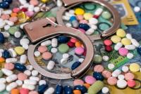 Closed handcuffs with colorful pills on Australian dollar background | Image Credit: RomanR | stock.adobe.com