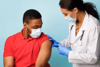 Man getting vaccinated by a woman, both wearing masks.
