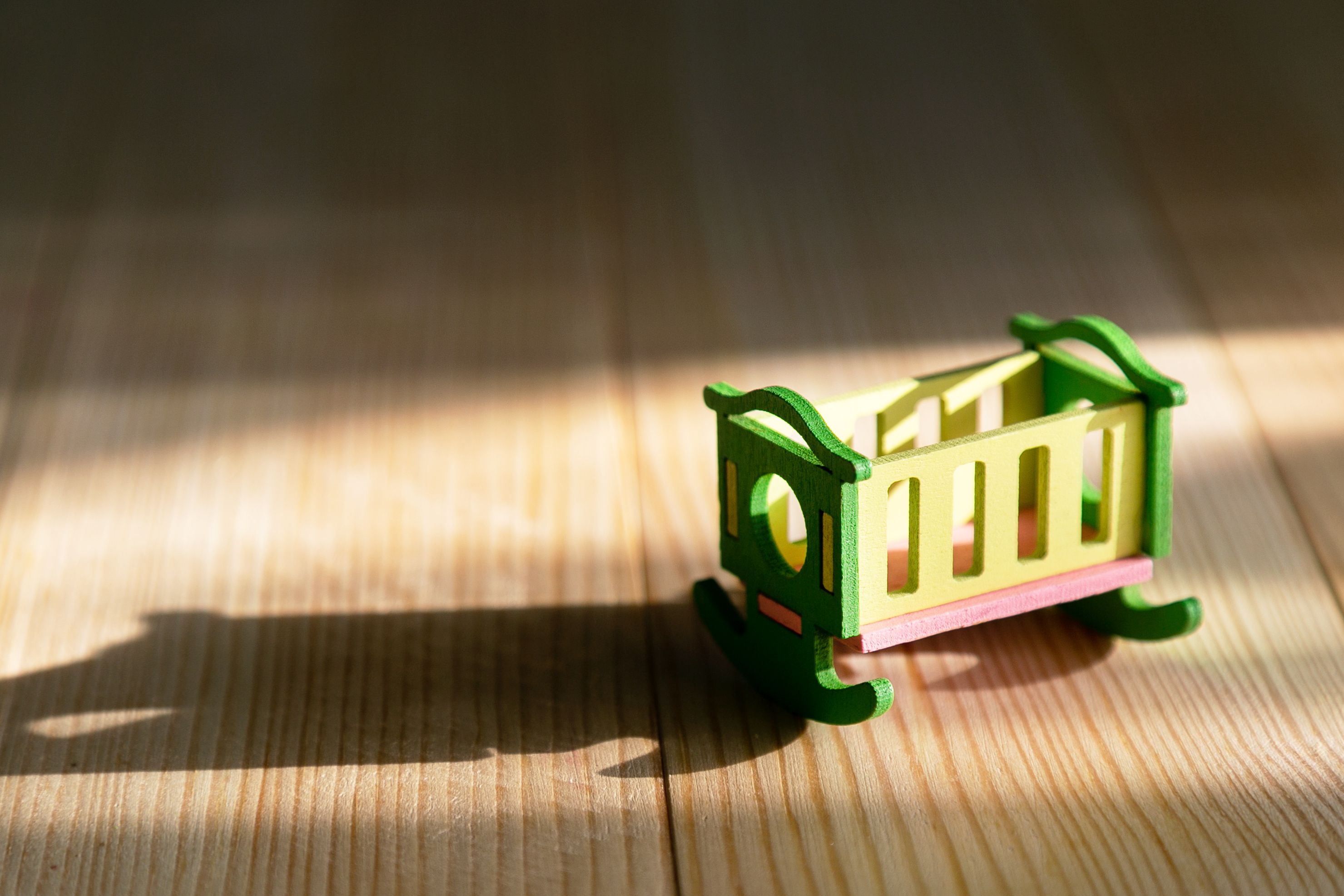 Empty crib on a wooden background. Infertility concept, lack of children in the family, empty crib.
