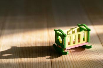 Empty crib on a wooden background. Infertility concept, lack of children in the family, empty crib.