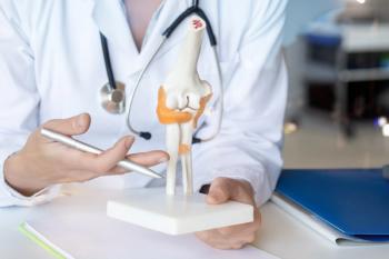 Health care professional with model of knee joint and bones -- Image credit: natali_mis | stock.adobe.com