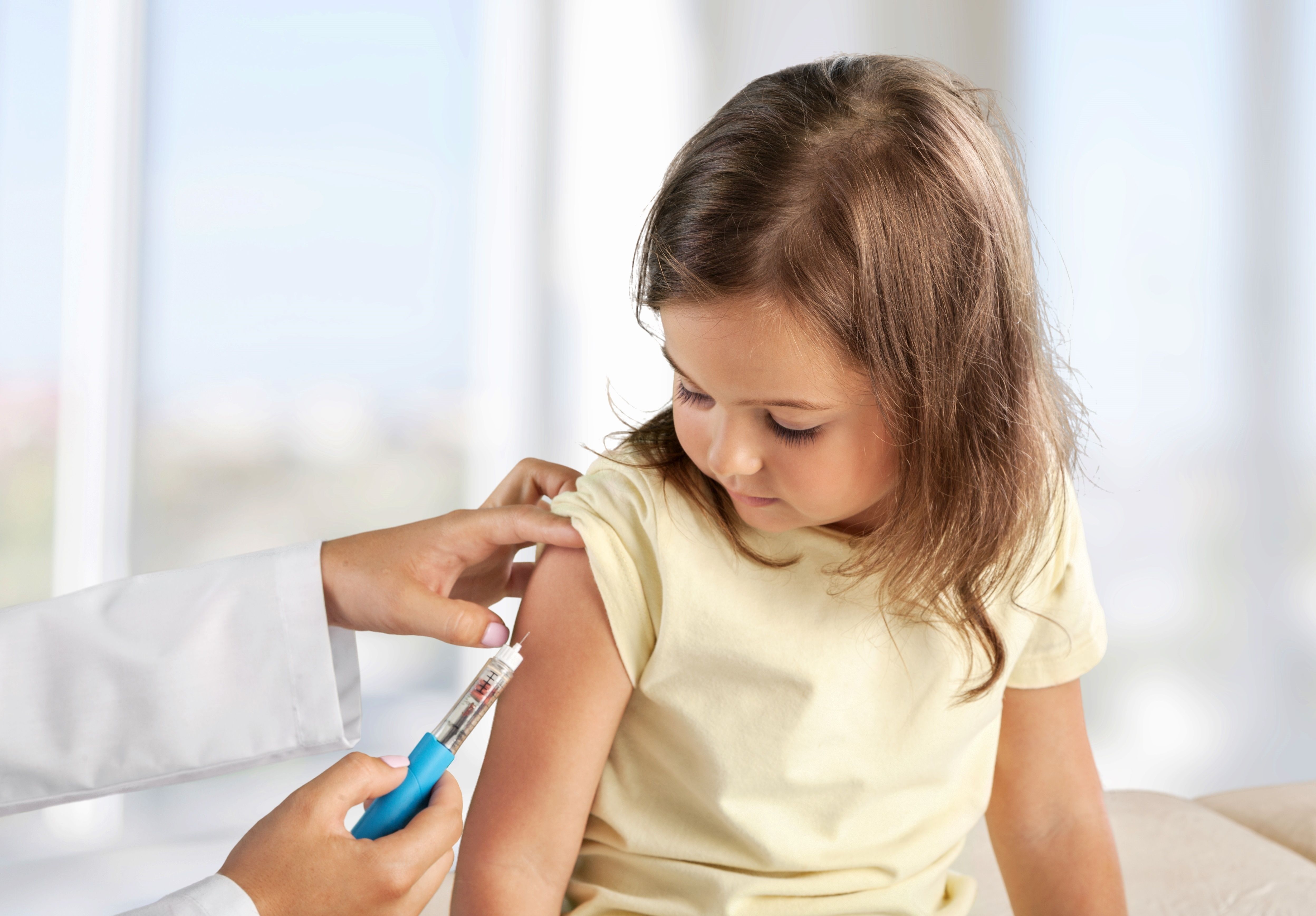 Female nurse giving an arm injection to a child. Little kid in getting a shot at a modern vaccination center. - Image credit: BillionPhotos.com | stock.adobe.com