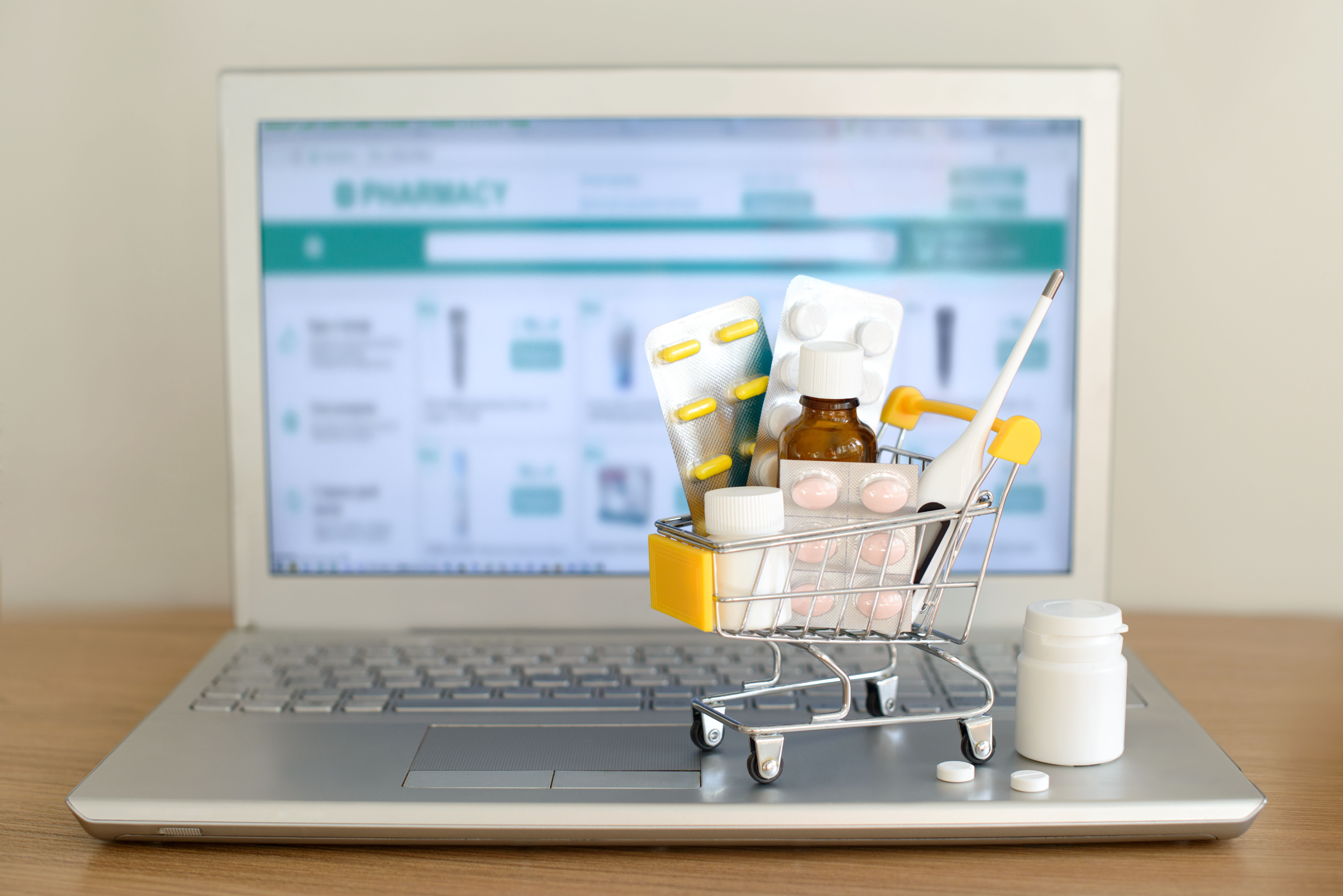 Shopping cart toy with medicaments in front of laptop screen with pharmacy web site on it. Pills, blister packs, medical bottles, thermometer set. Health care and internet shopping. | Image Credit: evso | stock.adobe.com Shopping cart toy with medicaments in front of laptop screen with pharmacy web site on it. Pills, blister packs, medical bottles, thermometer set. Health care and internet shopping. | Image Credit: evso | stock.adobe.com