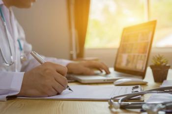 Medical professional researching on a laptop while taking notes