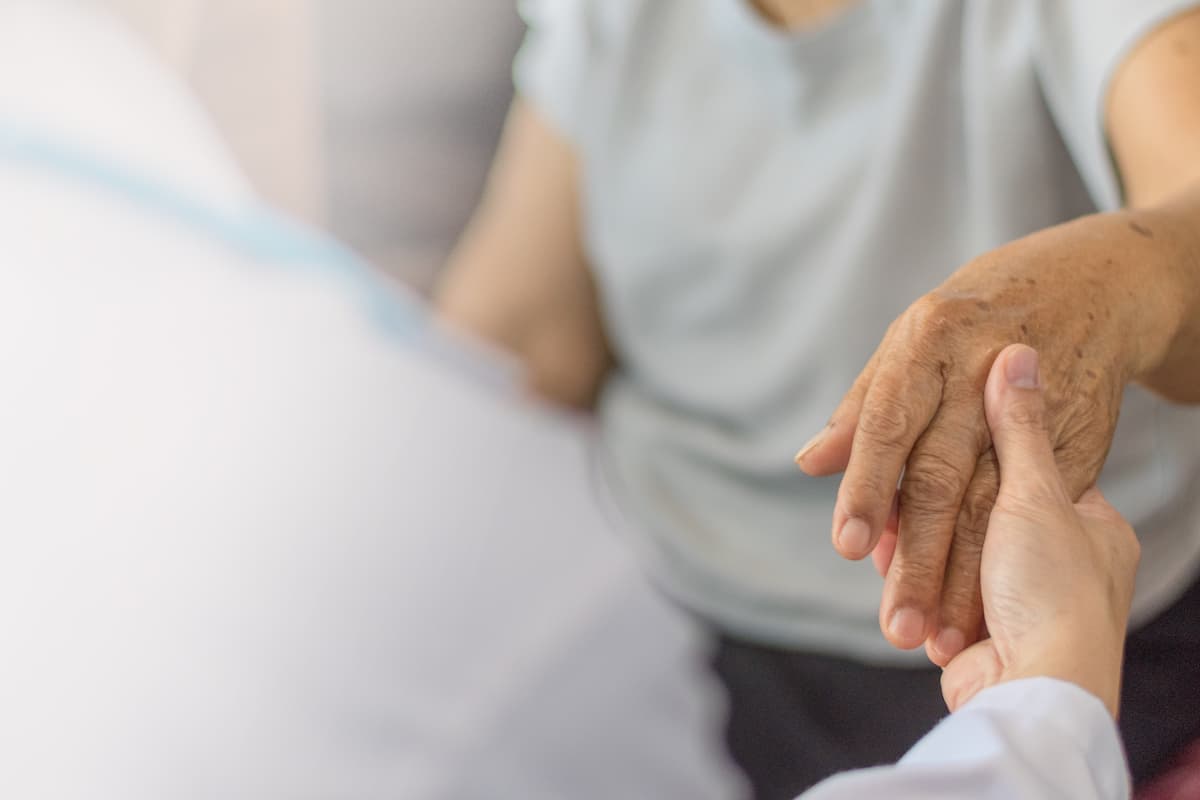 Parkinson and alzheimer female senior elderly patient hand with physician doctor exam in hospice care room.