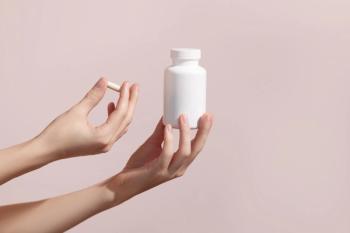 Woman holding pill and blank white plastic tube on pink background. Packaging for pill, capsule or supplement. Medic product branding mockup. | Image credit: LeviaUA- stock.adobe.com